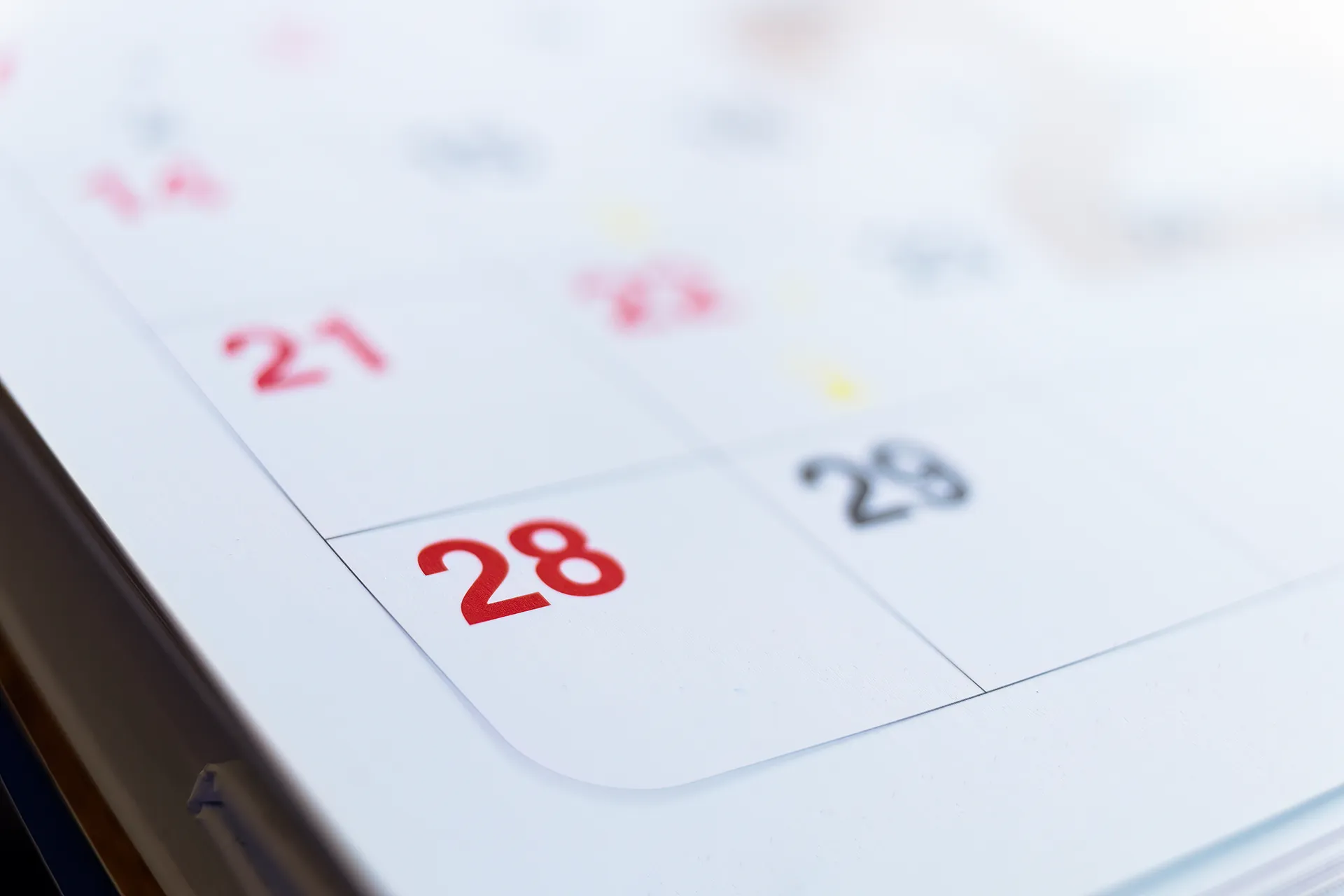 Close-up of a calendar showing the date 28 in red and black numbers.